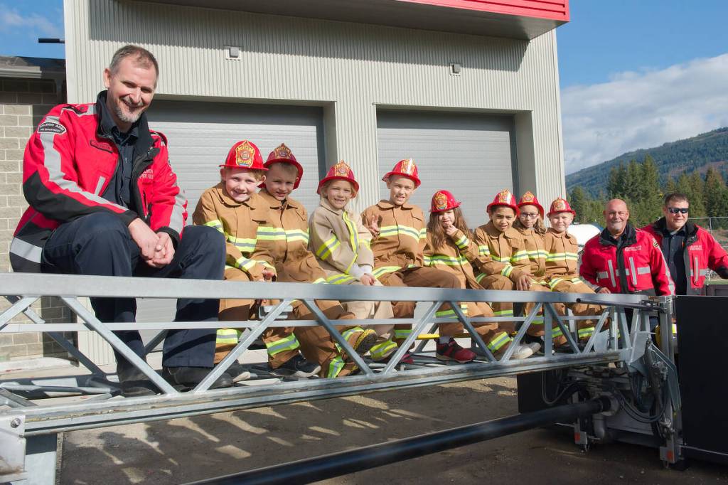 Salmon Arm Fire Department Lt. Tyler Stevenson, Fire Chief Brad Shirley and firefighter Chris Scarborough share a moment on the ladder of Tower 3 with their young Fire Chiefs for a Day at Fire Hall #2 on Friday, Oct. 17, 2025. (Lachlan Labere-Salmon Arm Observer)